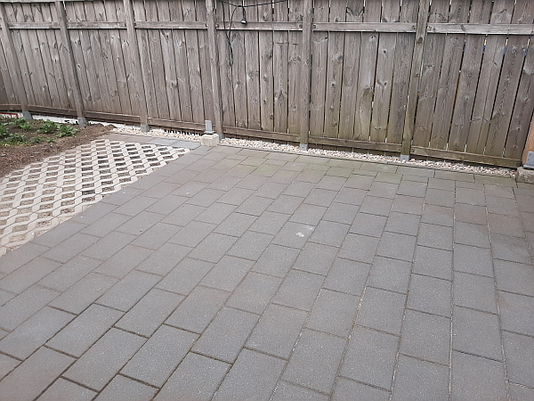 Ein kleiner Pool für den Garten. Hier zu sehen: Untergrund vorbereiten. Im Hintergrund ist ein Lattenzaun - im Vordergrund eine gepflasterte bereits gereinigte Fläche. Damit das Badevergnügen bald losgehen kann.