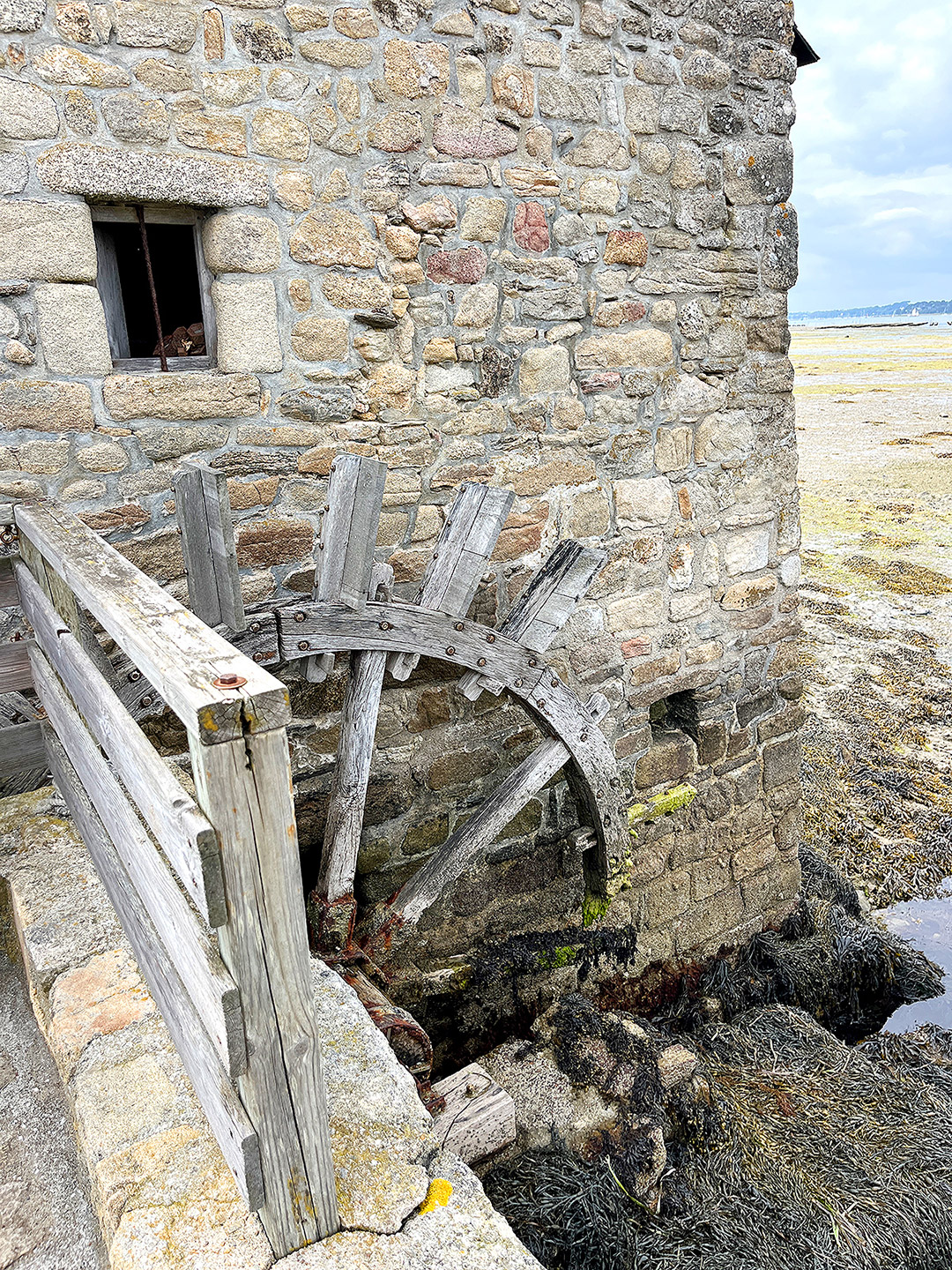 Bretagne mit Kindern - Südküste Bretagne mit Kindern - Südküste: Hier zu sehen: Die Gezeitenmühle auf der Ile d´Arz im Golfe du Morbihan. Man sieht ein Gebäude mit einem Mühlrad aus Holz. Es ist Ebbe.
