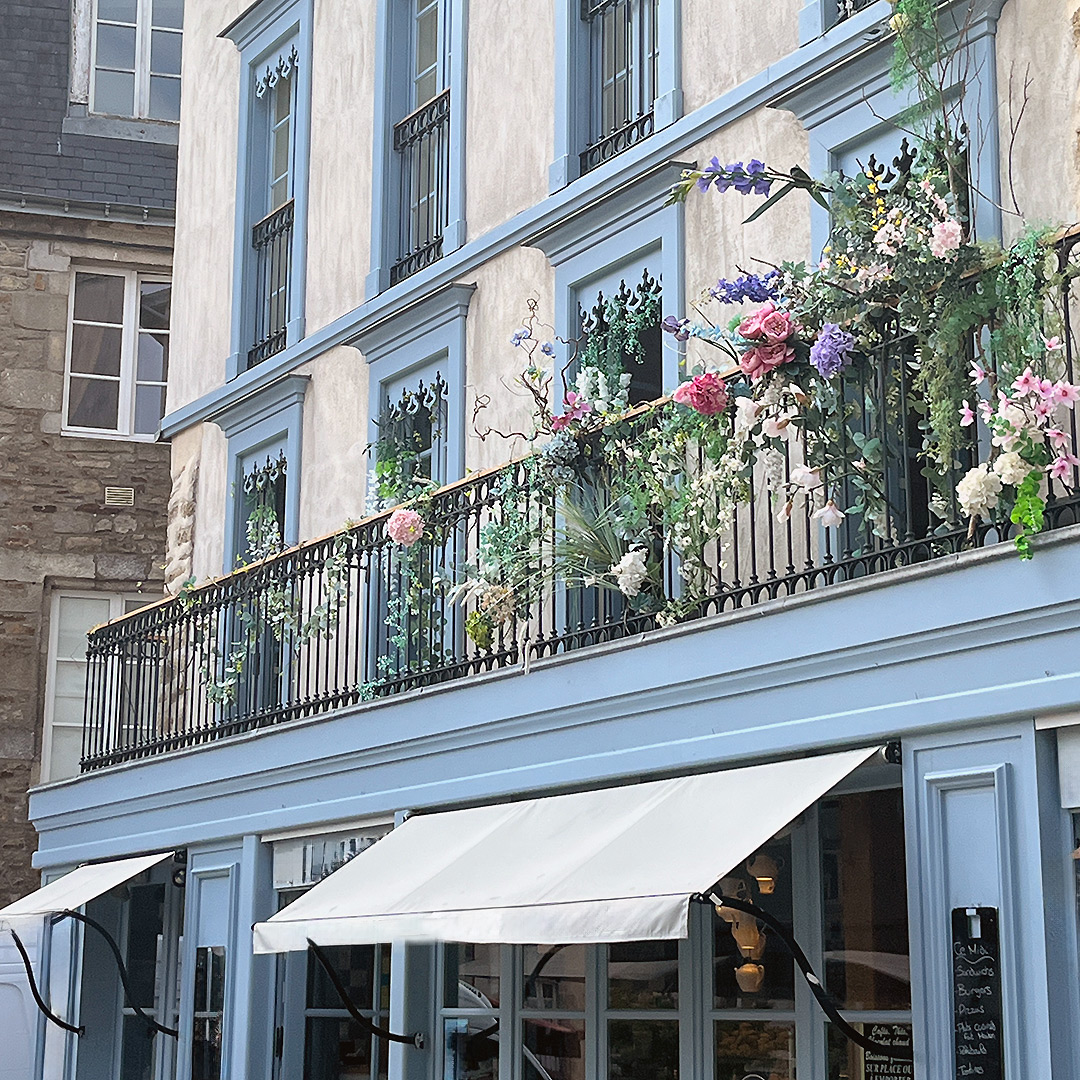 Bretagne mit Kindern - Südküste Belle-Ile-en-Mer mit Kindern. Ausflug in die Stadt Vannes, hier zu sehen eine Fassade einer Bäckerei mit hellblauen Fensterrahmen und Blumen dekoriert.
