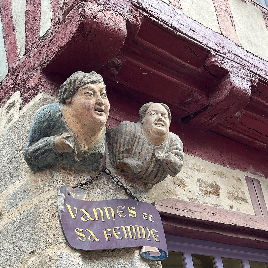 Bretagne mit Kindern - Südküste Südliche Bretagne - Ausflug in die Stadt Vannes: Das heimliche Wahrzeichen der Stadt Vannes - zwei Holzfiguren, Mann und Frau, die an einer Fachwerkfassade angebracht sind.