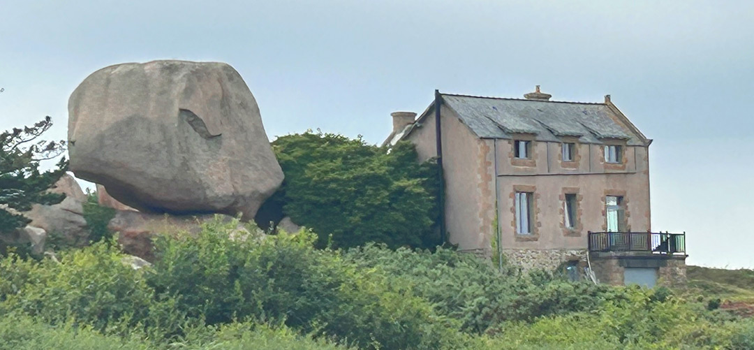 Bretagne mit Kindern - Westküste Bretagne - Cote-de-Granit-Rose. Hier zu sehen ein Fels, der genauso groß ist wie das Haus daneben. Als hätte ein Riese ihn dort abgelegt.
