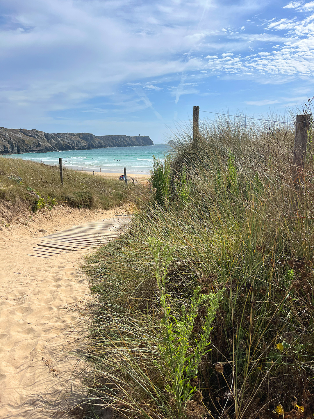 Bretagne mit Kindern - Westküste Bretagne mit Kindern. Hier der Strandaufgang (Sandweg) zur Plage de Pen Hat. Zu sehen ist blaues Wasser und Klippen im Hintergrund.