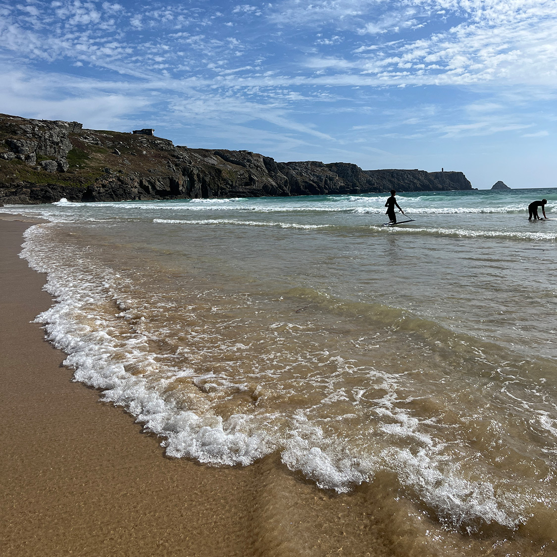 Bretagne mit Kindern - Westküste Bretagne mit Kindern - HIer zu sehen die Brandung vor einer eindrucksvollen Küstenlandschaft mit Surfern im Wasser.