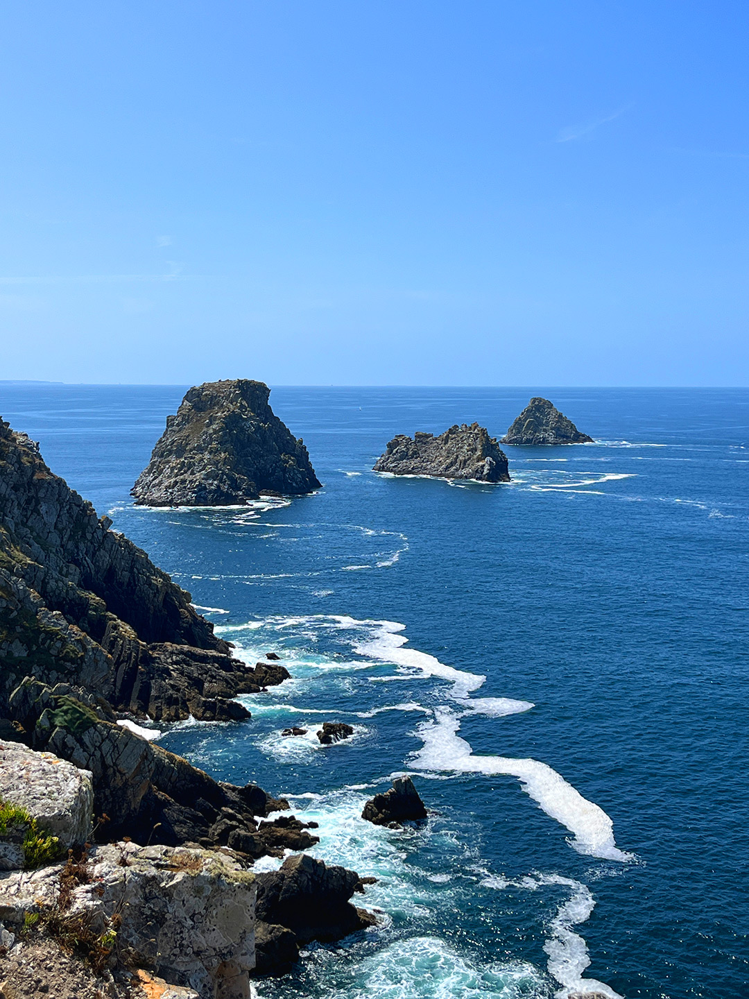Bretagne mit Kindern - Westküste Den Westen der Bretagne mit Kindern entdecken. Hier zu sehen die Pointe de Pen Hir. Eine Felsformation. Es ragen drei Felsen aus dem Wasser.