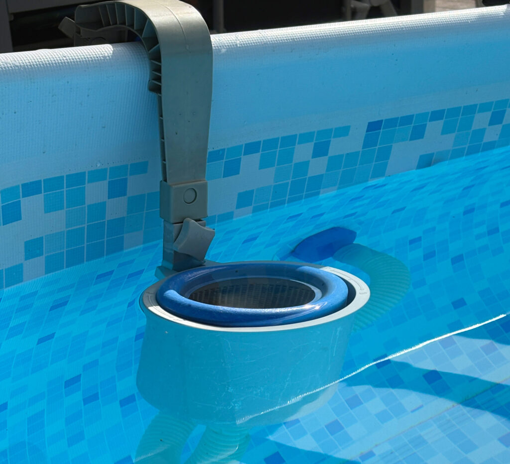 familie-entdeckt.de - Thema Poolpflege - hier zu sehen: ein Skimmer in grau und blau, der am Rand eines Aufstellpools befestigt ist.